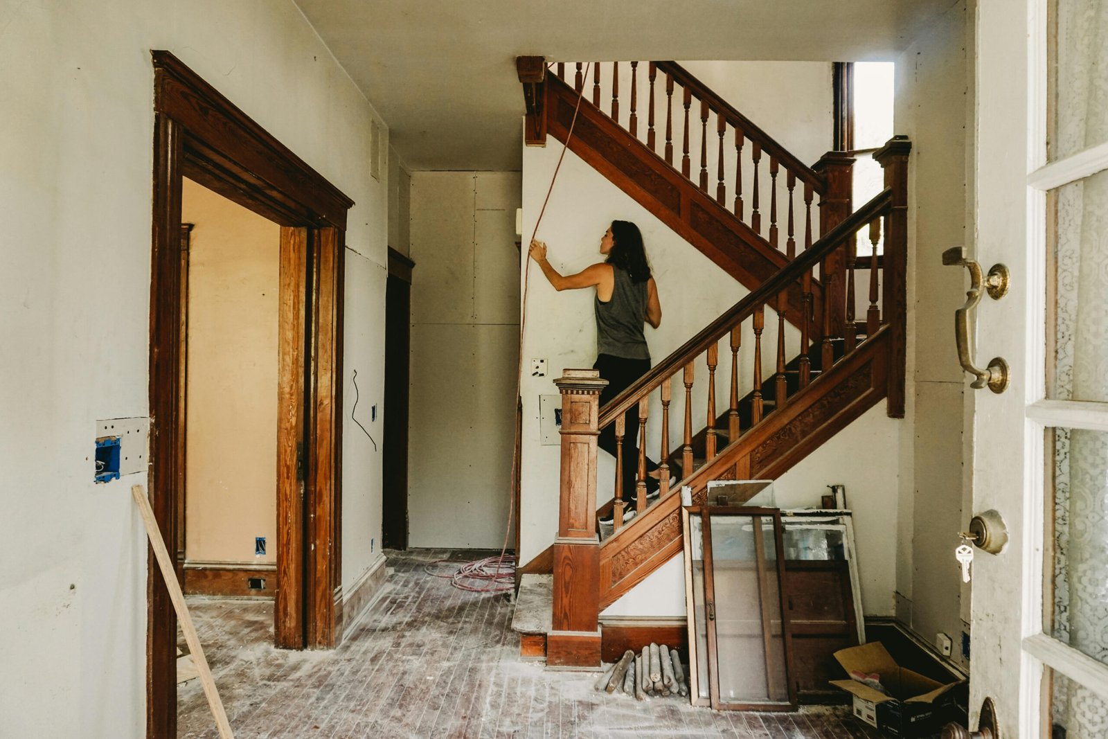 Femme traçant un mur sur un escalier en bois dans une pièce en rénovation.